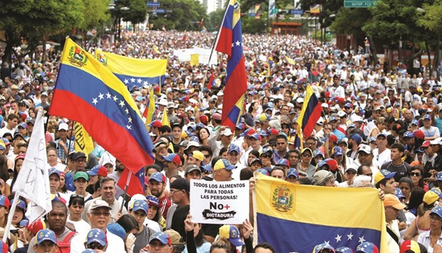 Demonstrators hold Venezuelan flags and a sign reads: u2018 All the food for all the people! No more dictatorship u2018 while rallying against Venezuelau2019s President Nicolas Maduro in Caracas, Venezuela, yesterday.