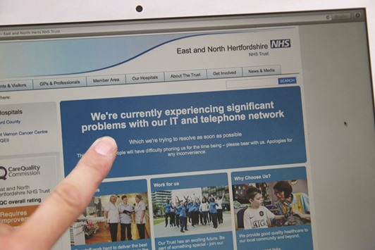 In this posed picture photograph, a woman points to the website of the NHS: East and North Hertfordshire notifying users of a problem in its network, in London yesterday.  Several British hospitals were hit by cyber attacks yesterday, the countryu2019s health service said, forcing some to divert ambulances to other clinics and urge people not to try to contact their doctors.
