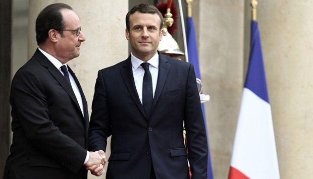 French newly elected President Emmanuel Macron (R) is welcomed by his predecessor Francois Hollande