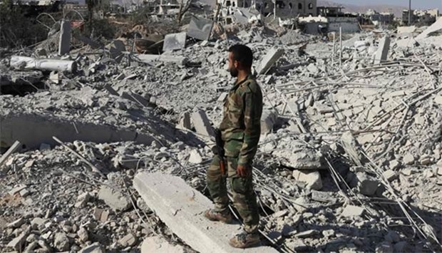 A member of the Syrian pro-government forces stands on the rubble of destroyed buildings as troops advance through Qaboun district, on the outskirts of Damascus, on Saturday.