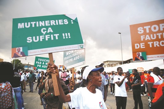 A supporter of the ruling party Rally of the Republicans holds a placard during a demonstration against the mutiny close to the military headquarters in Abidjan. The placard reads: u2018Mutineers: itu2019s enoughu2019.