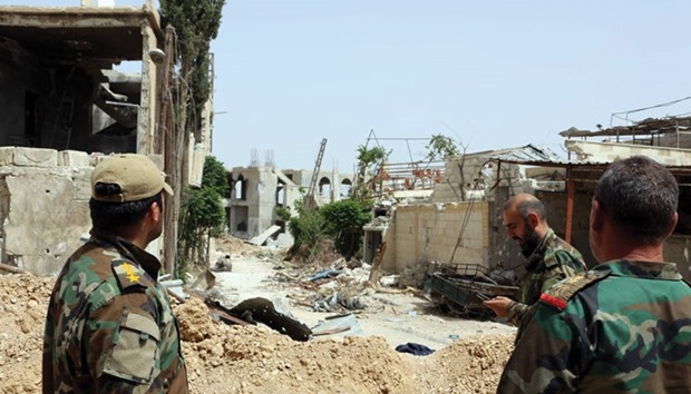 Syrian government forces look at a damaged street in Damascusu2019 northeastern Qabun suburb yesterday.