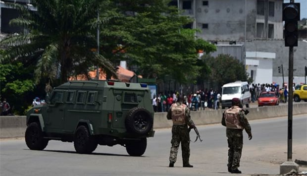 People walk past mutinous soldiers as they stand in their vehicles and block the street going to the Akouedo's military camp, in Abidjan, on Monday.