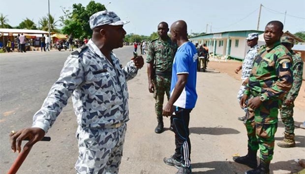 A policeman talks with mutinous soldiers as they prepare to leave the block at the entrance of Bouake on Tuesday.