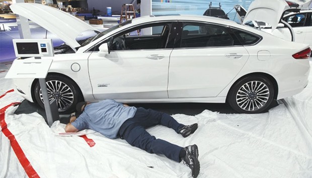 A worker prepares a Ford Fusion Energi mid-size vehicle at the companyu2019s booth during preparations ahead of the Los Angeles Auto Show in November 2016. The job cuts at Ford are expected to be outlined as early as this week and mostly target salaried employees, the Wall Street Journal said, citing unidentified people briefed on the plan.