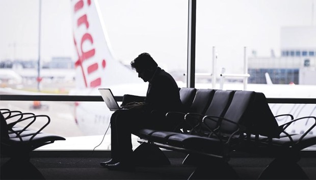 A passenger uses a laptop computer as an aircraft operated by Virgin Australia Holdings stands outside a gate at the domestic terminal of Sydney Airport on August 29, 2013. Carriers are bracing for operational chaos at European airports after the US Department of Homeland Security said last week it might expand to Europe a ban imposed in March on US-bound flights from 10 Middle Eastern airports. The new security protocol could mean longer security lines, heightened delays, boarding gate confusion, and yet more hassles for fliers.