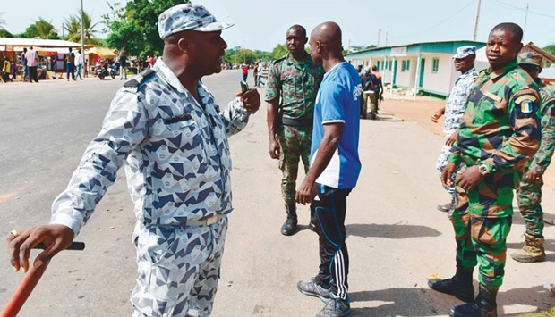 A policeman talks with soldiers as they prepare to leave a roadblock at the entrance of Bouake yesterday.