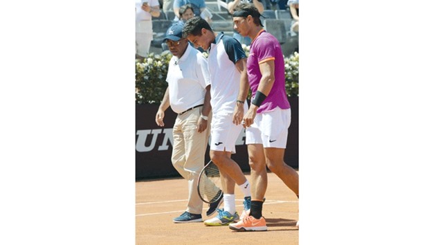 Rafael Nadal of Spain (R) helps Nicolas Almagro of Spain who was forced to abandon the match after an injury yesterday.