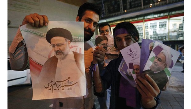 A supporter of Iranian President and election candidate Hassan Rouhani (right) stands alongside another of candidate Ebrahim Raisi (left) as they distribute brochures ahead of the presidential election in the streets of Tehran yesterday.