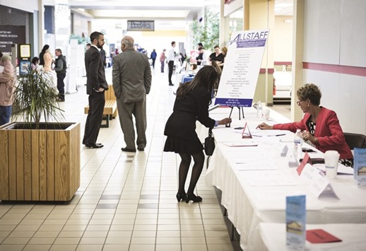 A job seeker takes a business card at the Laconia Job & Resource Fair at Belknap Mall in Belmont, New Hampshire. Initial claims for state unemployment benefits decreased 4,000 to a seasonally adjusted 232,000 for the week ended May 13, declining for three consecutive weeks, the US Labor Department said.