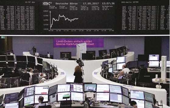 Traders work in front of the German share price index, DAX board, at the stock exchange in Frankfurt yesterday. European and Asian stocks slid yesterday on fears that a growing crisis surrounding US President Donald Trump could lead to his impeachment and shatter any chances of his economy-boosting agenda being implemented.