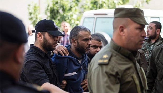Hamas security forces escort Abdallah al-Nashar (centre), a Palestinian man convicted of the murder of Hamas military commander Mazen Faqha, out of the military court in Gaza City on Sunday.