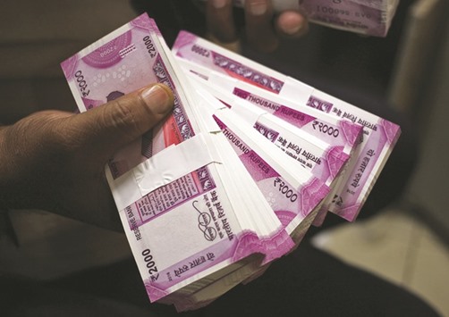 A cashier displays Indian rupee banknotes inside a bank in Jammu. Foreign holdings of rupee-denominated government and corporate debt have surged by Rs768bn so far in 2017, after falling Rs306bn last year.