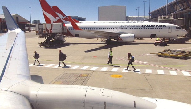 An official watches passengers as they walk along the tarmac to board a Qantas Airways Boeing 737-800 plane at Sydneyu2019s domestic airport terminal. The Australian government said yesterday it will build an A$5bn ($3.76bn) second international airport in Sydney, ending decades of indecision on the project.