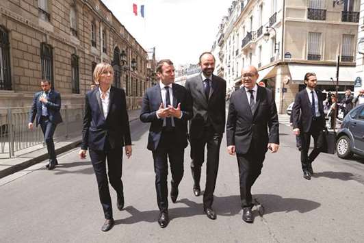 President Emmanuel Macron, flanked by Minister for European Affairs Marielle de Sarnez, Prime Minister Edouard Philippe, and Foreign Affairs Minister Jean-Yves Le Drian, walk to the British embassy to sign a book of condolences for the 22 killed the day before in an attack in Manchester claimed by the Islamic State group.