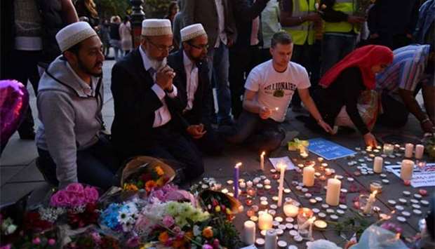 People pray and light candles set up in front of floral tributes in Albert Square in Manchester on Tuesday.
