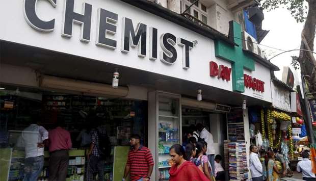 People walk past a chemist shop in Mumbai