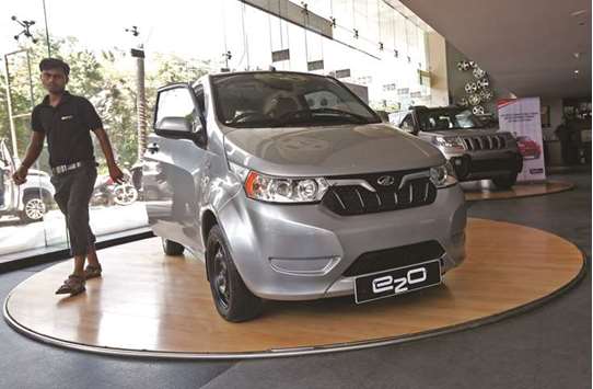 An employee walks past a Mahindra e2o electric car on display at a showroom in Mumbai. Mahindra Electric Mobility, a subsidiary of the automaker, aims to expand its capacity to make electric vehicles almost 10-fold to 5,000 units a month in two to three years, Mahindrau2019s managing director Pawan Goenka said.