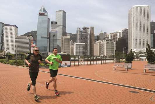 People jog in front of office towers at the financial central district in Hong Kong. Hong Kong yesterday hit back at a decision by Moodyu2019s to cut its credit rating on the city, which the agency said was becoming increasingly close to mainland China.