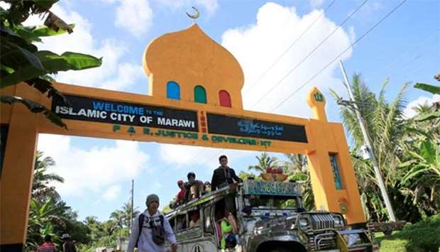 A public transport vehicle carrying residents is driven past a marker towards an evacuation centre in Marawi city, on Friday.