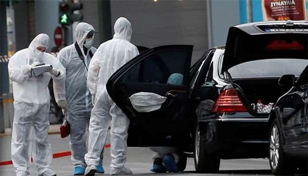 Forensic officers inspect the car of former Greek prime minister Lucas Papademos following the detonation of an envelope injuring him and his driver, in Athens.