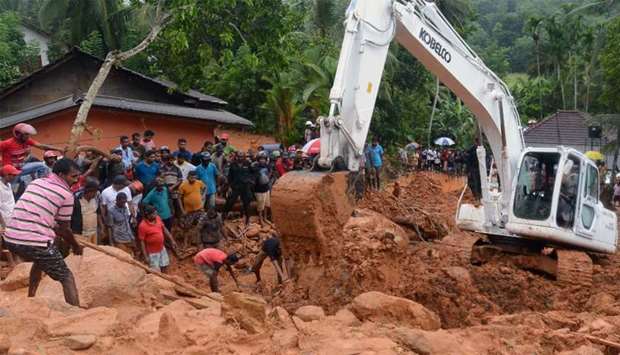 Sri Lankan military rescue workers and villagers search for survivors at the site of a mudslide