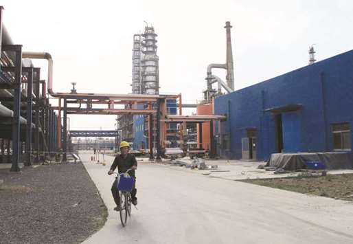 An employee rides a bike on a road near refinery plants of Chambroad Petrochemicals, in Shandong province, China. The Opec-led decision to extend a production cut to March 2018 disappointed financial investors, prompting an exit from oil futures markets, while refiners in Asia were mostly concerned with whether it meant they would need to go hunting for crude.