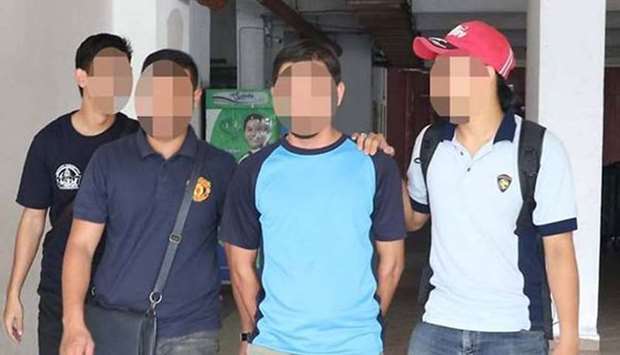 Malaysian police are seen with one of the six Islamic State suspects.