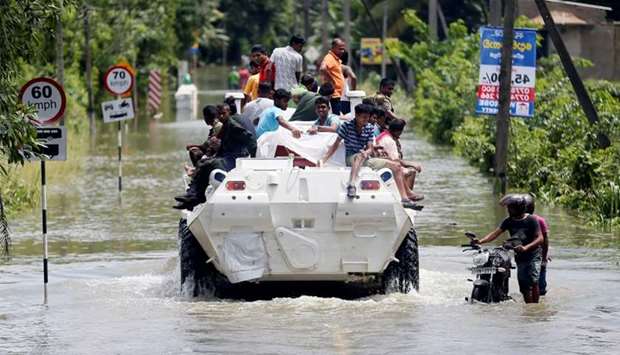 People travel on top of a armoured personnel carrier on a flooded road