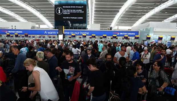People wait with their luggage at the British Airways check in desks at Heathrow Terminal 5 in London on Sunday.