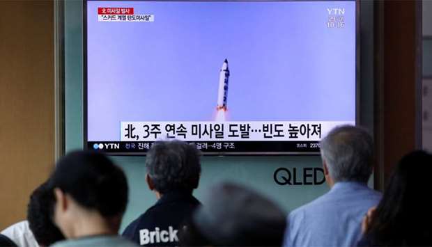 People watch a television broadcasting a news report on North Korea firing a missile