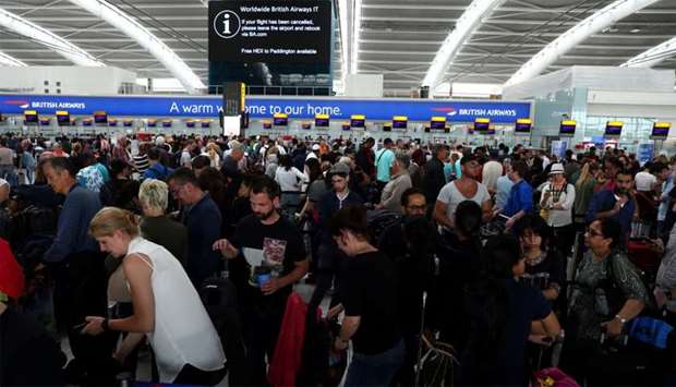 People wait with their luggage at the British Airways check in desks at Heathrow Terminal