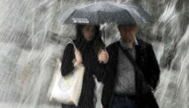 A couple protect themselves with an umbrella while walking under heavy rain in Moscow's Alexander Garden on Monday.