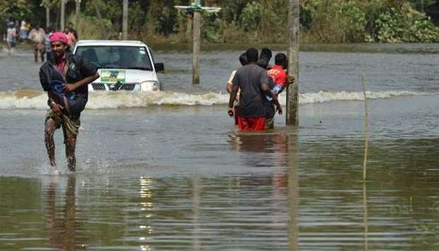 Sri Lankans make their way through floodwaters in Bulathsinhala, Kalutara district on Monday.