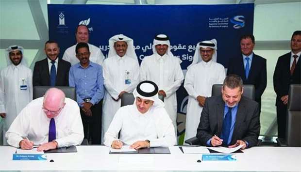 An official of the SC and representatives of the two Qatari companies sign the agreements as other officials look on.