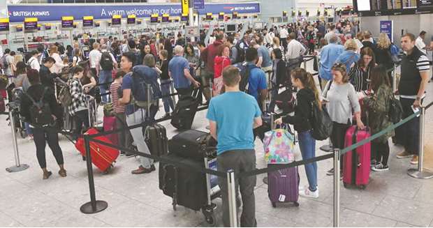 Passengers wait to check-in at a British Airways desk inside Terminal 5 of Londonu2019s Heathrow Airport yesterday.