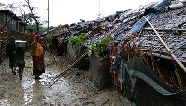 Rohingya refugees walk next to huts in a makeshift camp in Bangladesh's Cox's Bazar district on Tuesday after Cyclone Mora made landfall in the region.