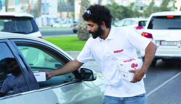 A volunteer from Ooredoo hands over a pack of dates and water to a motorist.
