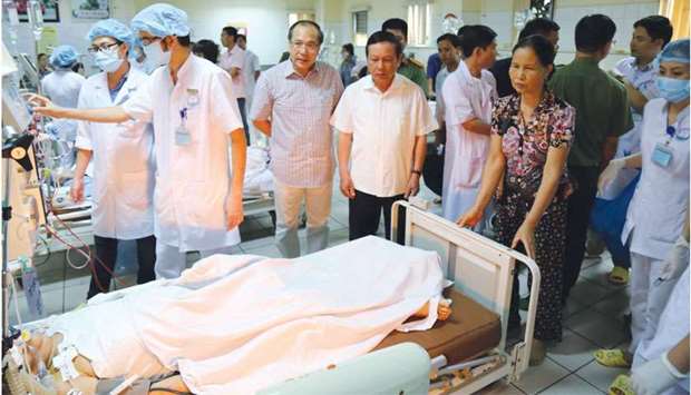 Officials and family members stand next to patients undergoing kidney dialysis in an intensive care unit at hospital in the northern city of Hoa Binh late on Monday.