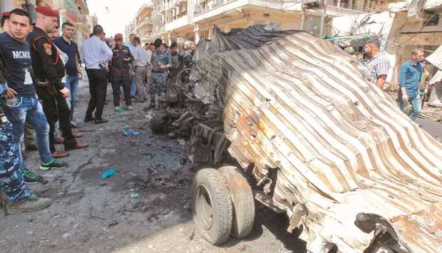 Iraqis gather at the site of a car bomb explosion near Baghdadu2019s Al-Shuhada Bridge yesterday.