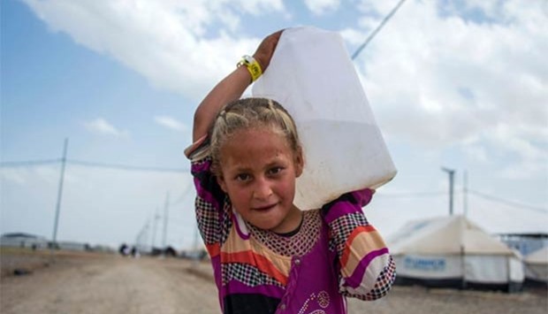An Iraqi girl walks carrying water at a camp for internally displaced people in Hammam al-Alil on Wednesday.