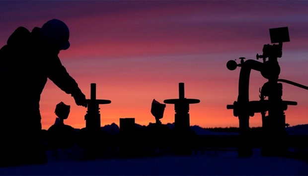 A worker checks the valve of an oil pipe at an oil field