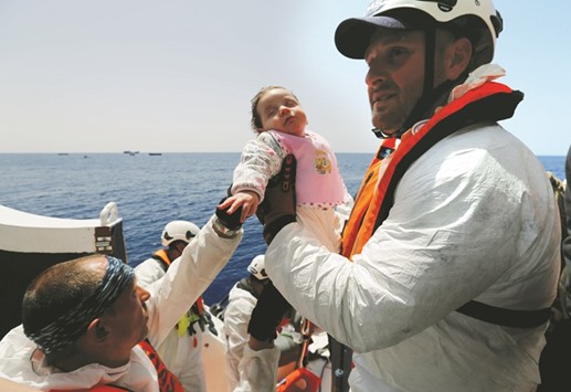 A baby migrant is brought onto the Malta-based NGO Migrant Offshore Aid Station (MOAS) ship Phoenix during a rescue operation in the central Mediterranean, in international waters off the Libyan coastal town of Sabratha.