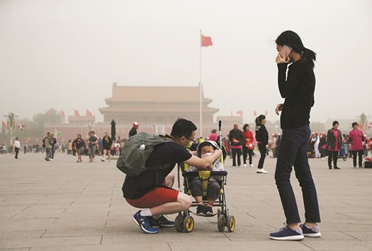 A man puts a mask on his son at Tiananmen Square as a dust storm hit Beijing yesterday.