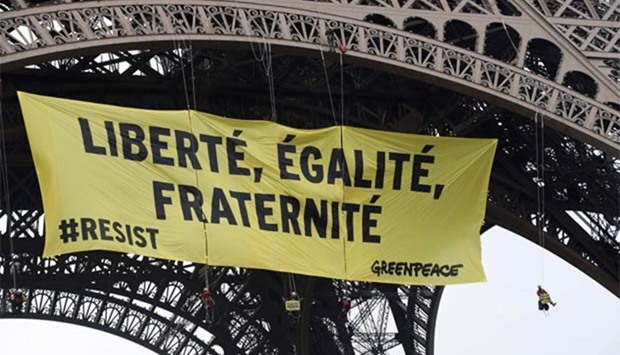 Greenpeace activists hang from cords after unveiling a banner reading ,liberty, equality, fraternity, on Eiffel Tower in Paris on Friday.