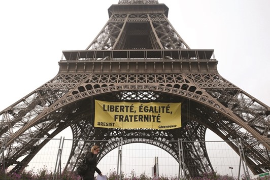 A woman walks past by a banner unfurled by Greenpeace activists on the Eiffel Tower, which reads  u2018Liberty, Equality, Fraternityu2019 in a call on French citizens to vote against Le Pen.