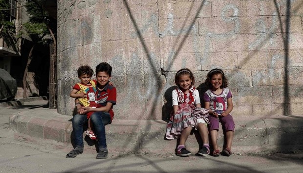 Syrian children pose for a photo near their house in the rebel-held town of Douma, on the eastern outskirts of Damascus