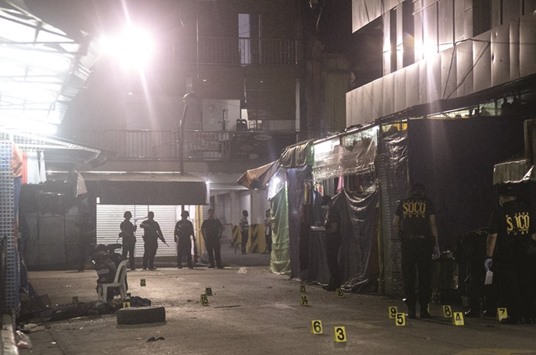 The body of a victim lies at the scene of an explosion as Philippines police officers examine the site in Quiapo in Manila yesterday.
