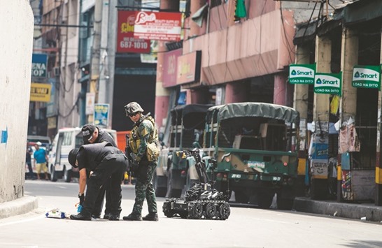 Bomb squad operatives and a bomb disposal robot inspect a suspicious package left near the Quezon bridge, in Quiapo, Manila yesterday.