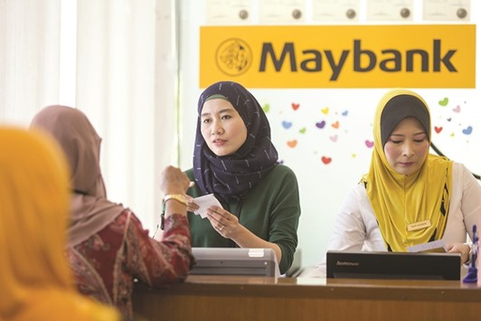 An employee serves a customer at the information counter inside a combined Malayan Banking Bhd (Maybank) and Maybank Islamic Bhd bank branch in Kuala Lumpur (file). Malaysia, which pioneered Shariah finance in the 1980s, aims to have 40% of its banking assets complying with the religion by 2020, from 28%, or a record 742bn ringgit at the end of 2016.
